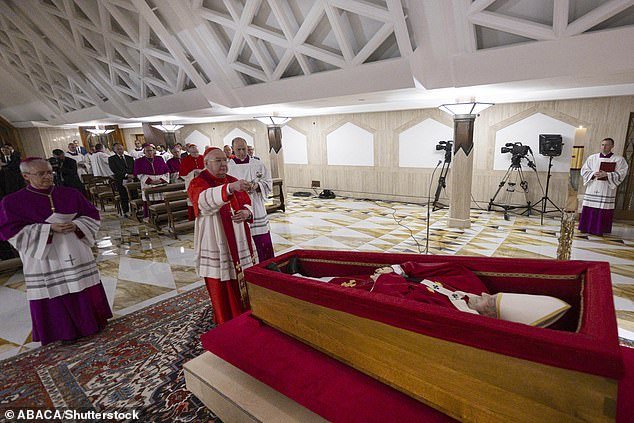 Pope Francis' body was placed in an open wooden casket in the chapel of the Domus Santa Marta hotel last night. Two Swiss Guards stood at attention as Vatican camerlengo Cardinal Kevin Farrell (centre) blessed Francis with holy water