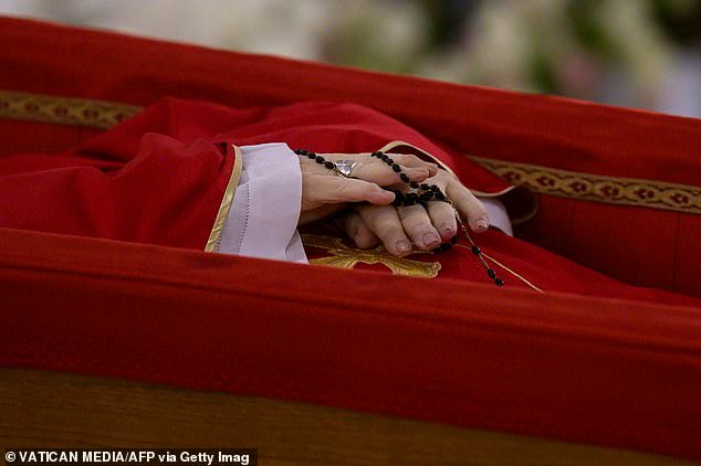 Pope Francis, dressed in red liturgical vestments and holding a rosary, is laid out in an open coffin at the Chapel of Santa Marta in The Vatican on Monday night
