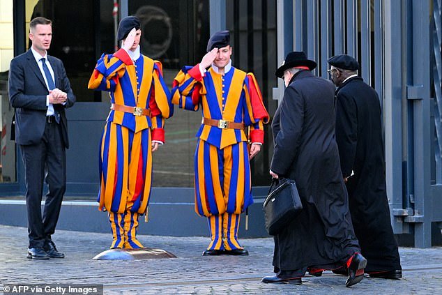 Cardinals (right) walk past two Swiss guards (2nd left and 3rd left) as they arrive at the Vatican today for the first meeting of the Congregation of Cardinals