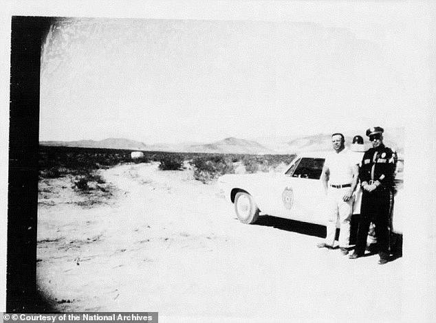 A police officer stands near to his patrol car outside the town of Socorro, New Mexico where a flying saucer was spotted in 1964