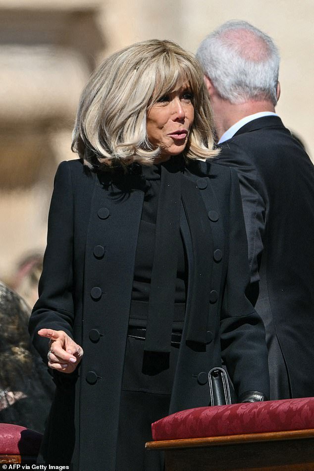 The French first lady added a thin belt and a simple bag to her look, as she arrived at the funeral holding her husband's arm
