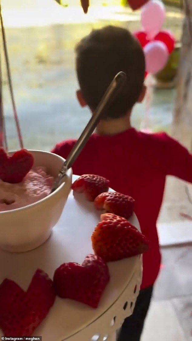 Meghan Markle shared a video (pictured) of herself making a treat for the children, featuring cream cheese bagels and strawberries cut into heart shapes, on Valentine's Day this year