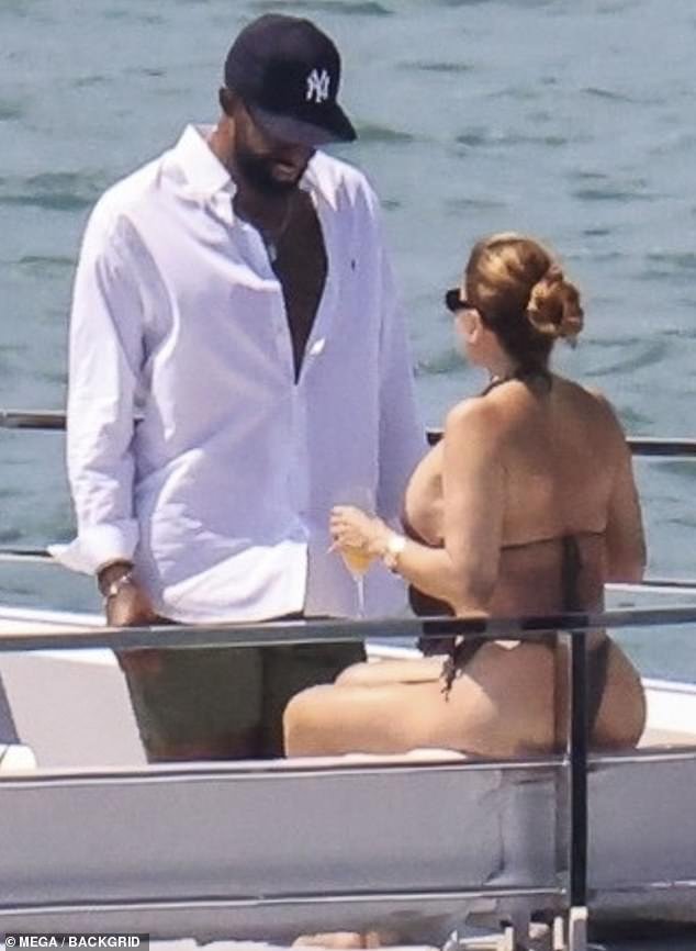 Serving up a generous helping of cleavage in her flatteringly cut swimsuit, she accessorized with shades and swept her caramel hair up into a bun