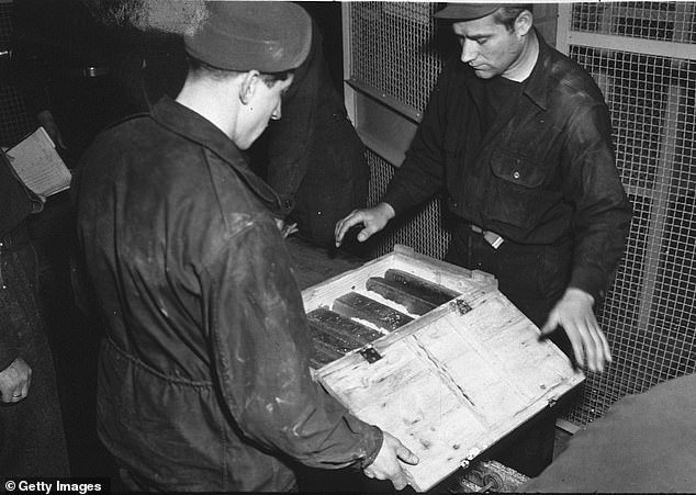 Workers inspect gold bars taken from Jews by the Nazis and stashed in a mine