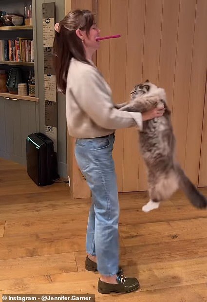 She swung her cat Moose around her living room while holding her phone in her mouth to film them together