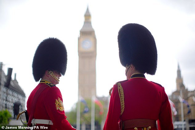 Members of the Household Division stand near Parliament Square in London today ahead of the military procession