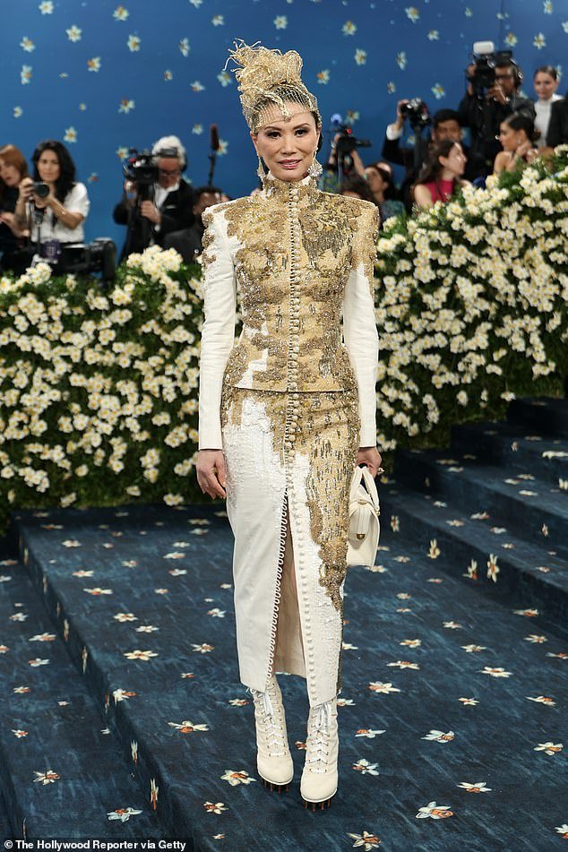 A lot going on! Entrepreneur Wendi Murdoch showed up to the Met Gala steps in a matching, two-piece suit set custom made by Thom Browne that featured gold detailing on the jacket and skirt. On her feet, she wore dramatic, white leather lace-up boots and a gold hat that almost looked like it was mad from wire