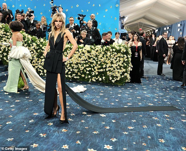 Suki Waterhouse walked the Met steps in a dress designed by Michael Kors, which featured a suit-style front and open back. She matched the plain look with boring pumps
