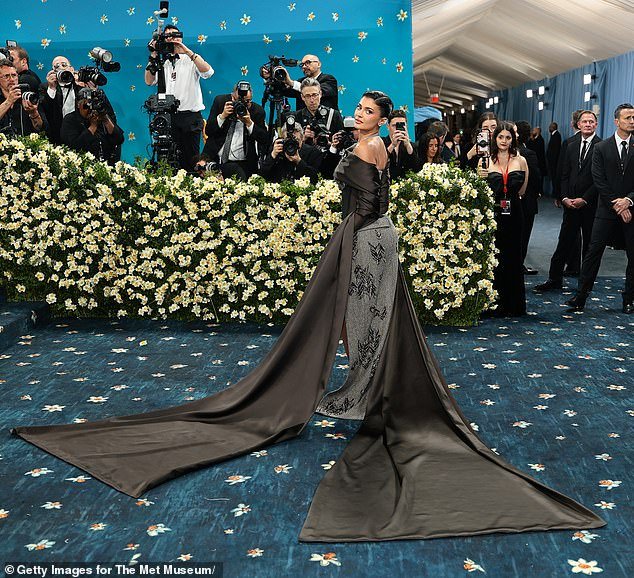 Jenner arrived with a dramatically long shawl draped around her arms before dropping the extra threads