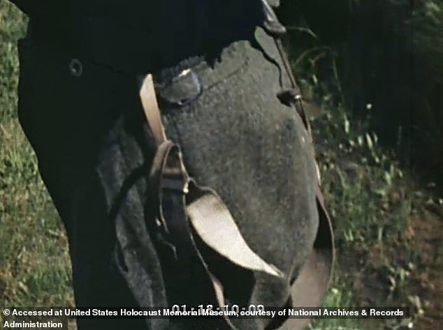 The camera pans down to the woman's trousers, with suspenders hanging down to her feet