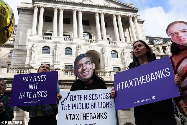 Demonstrators wearing masks depicting Britain's Prime Minister Rishi Sunak and the Governor of the Bank of England Andrew Bailey at a protest outside the Bank today