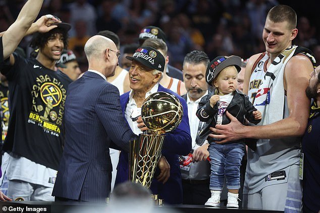Stan Kroenke (centre) accepts the NBA Finals trophy, the first in the history of the Denver Nuggets, who were led by Serbian icon Nikola Jokic (furthest right)