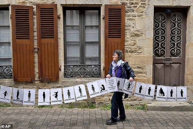 A woman holds a banner representing anonymous victims during a demonstration ahead of the verdict in the trial of Joel Le Scouarnec