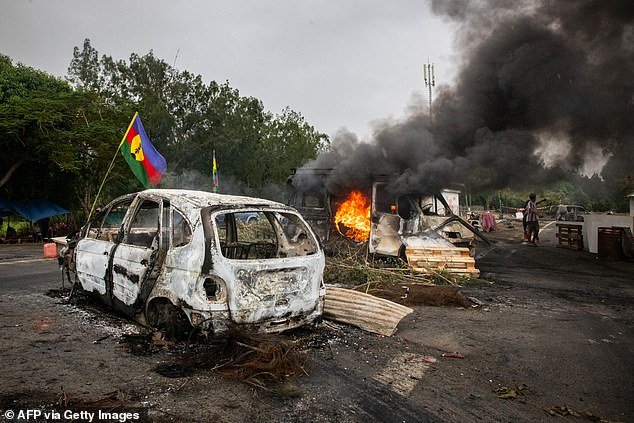 A Kanak flag waving next to a burning vehicle at a roadblock in New Caledonia on May 19, 2024