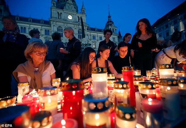 People light candles for the victims of a school shooting at Hauptplatz square in Graz, Austria
