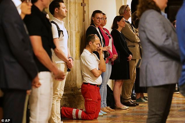 A member of rescue services knees on the floor and pray during a memorial service foloowing the shooting on June 10
