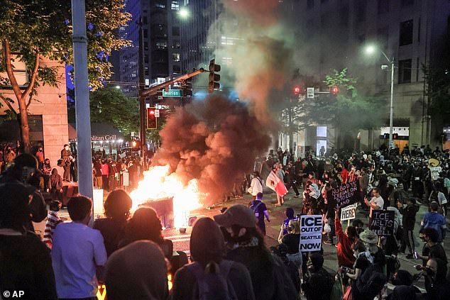 Protesters light a fire outside the Henry M. Jackson Federal Building in downtown Seattle on Wednesday during a demonstration to denounce the Trump administration's ICE raids