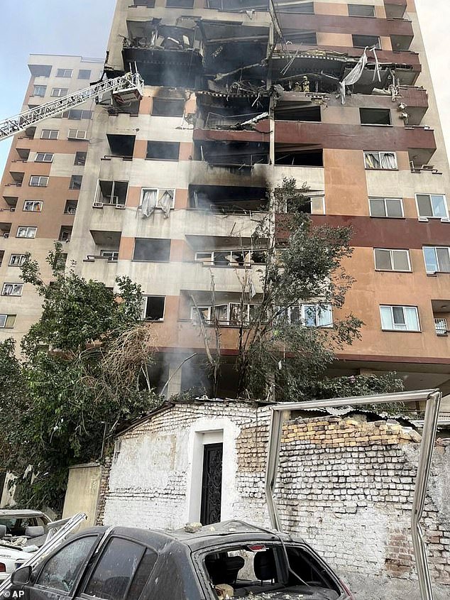 Firemen work at an apartment building after it was hit in Tehran, Iran, early Friday