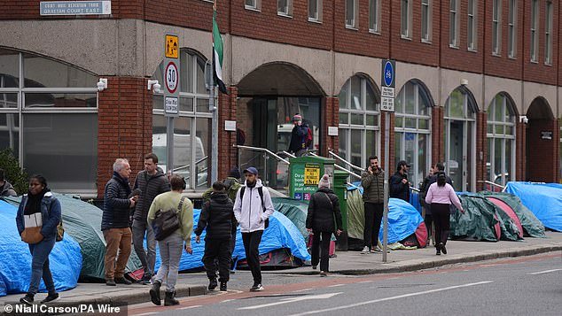 People walking past tents housing asylum seekers near to the International Protection Office, in Dublin