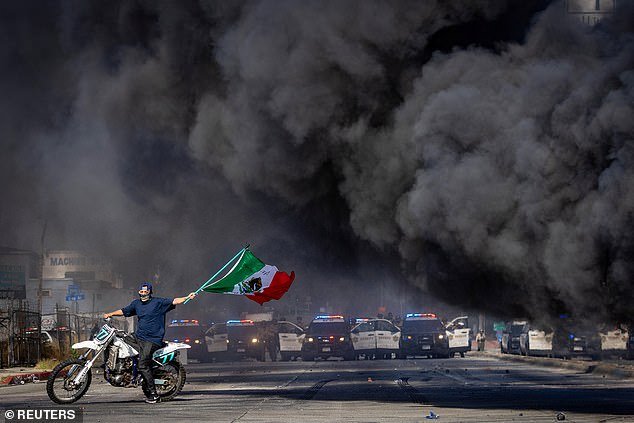 X users said the sheriff's office should focus on the chaos in their own backyard instead of getting involved in international issues. (Pictured: A masked protester biking around a blazing car in Los Angeles on June 7, 2025, amid anti-ICE riots in the California city)